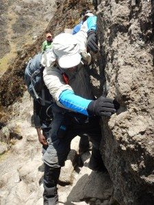A guide shows trekkers how to handle a rocky outcropping