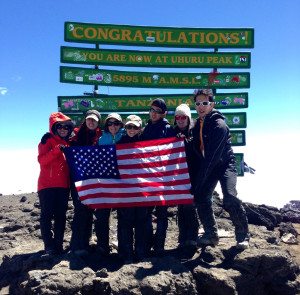 Trekkers hold an American flag at Uhuru peak