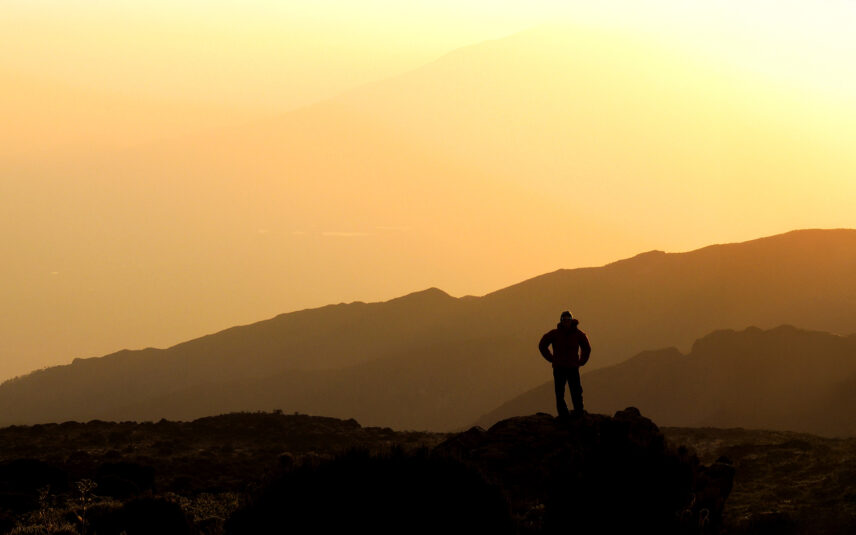 trekker looks at sunset view from shira camp on kilimanjaro