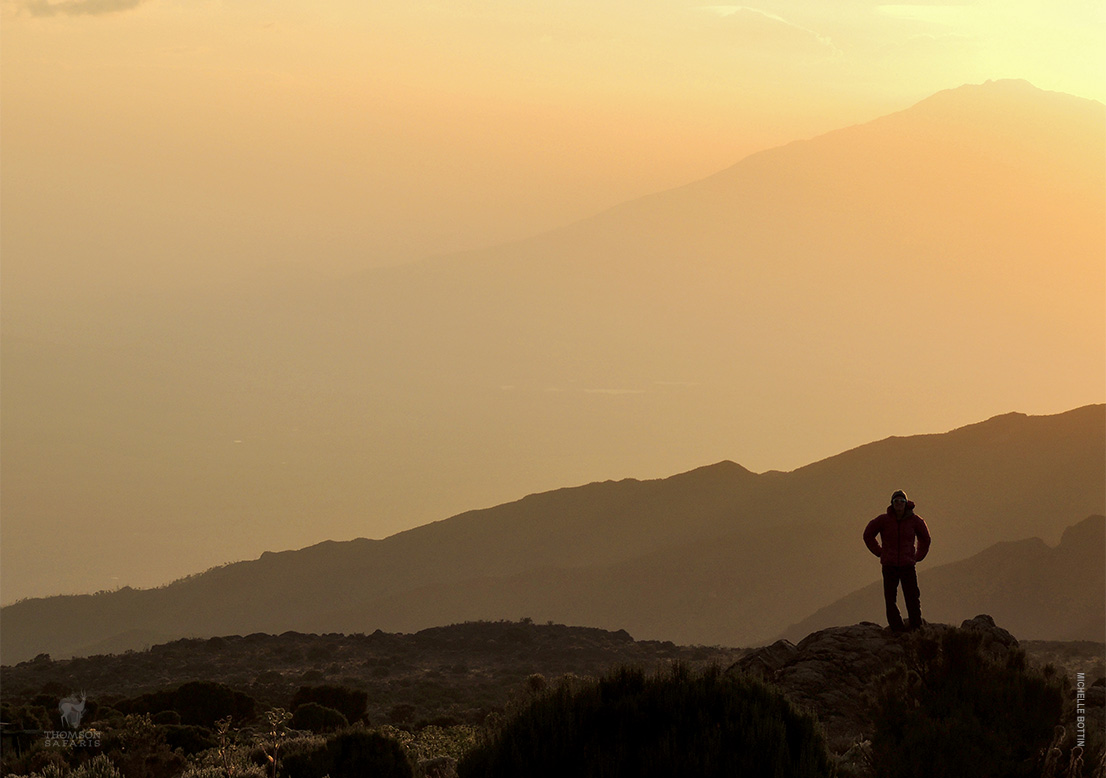 a man who was able to climb kilimanjaro, standing at the summit.