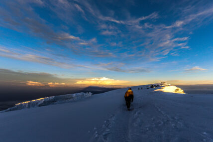trekking through snow to kilimanjaro summit at sunrise