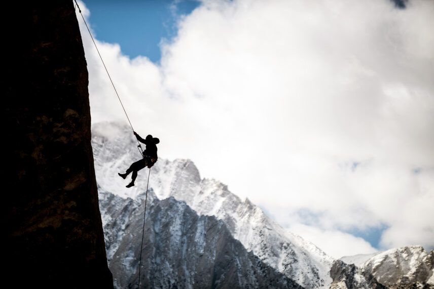 mountain climber rappelling down rock face