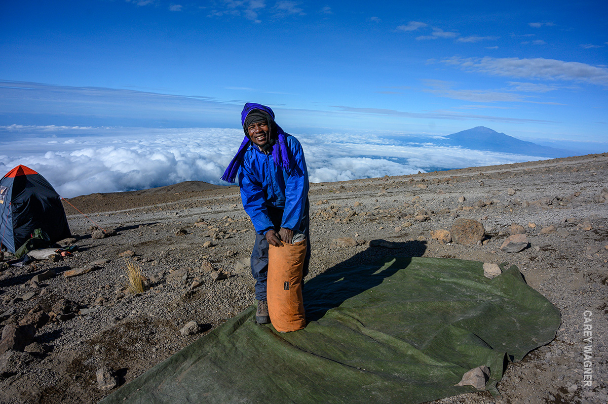 porter packing up tent at kilimanjaro camp