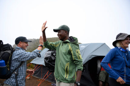 porter welcomes trekker to kilimanjaro camp