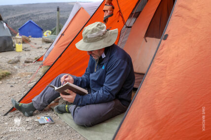trekker at camp writing and painting in travel journal