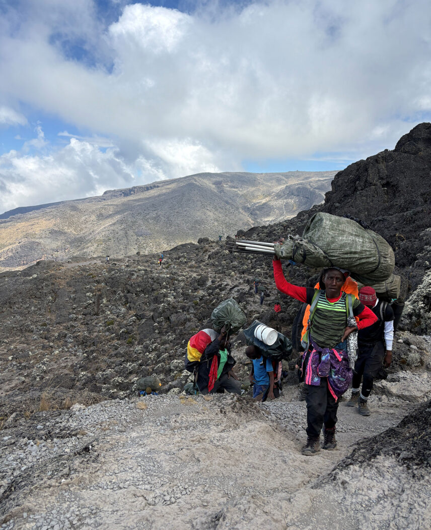 woman porter with bag on head working on mount kilimanjaro